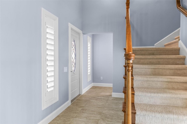 foyer entrance with stairway and baseboards