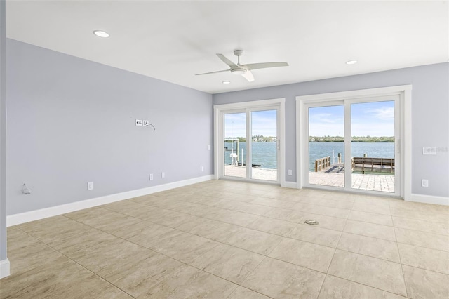 spare room featuring a ceiling fan, plenty of natural light, baseboards, and a water view