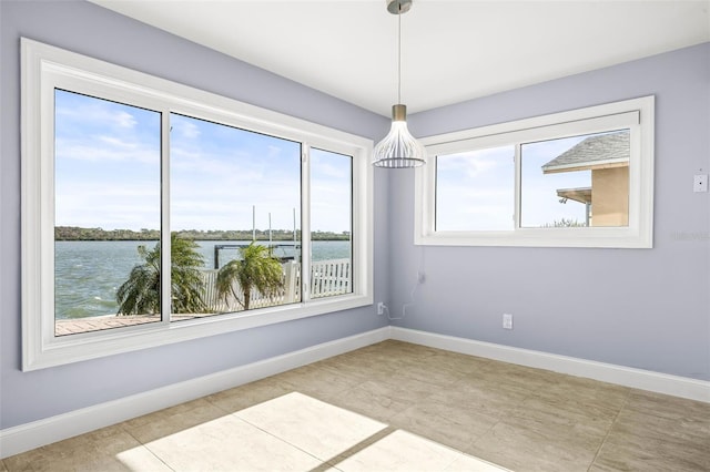 spare room featuring baseboards and a water view