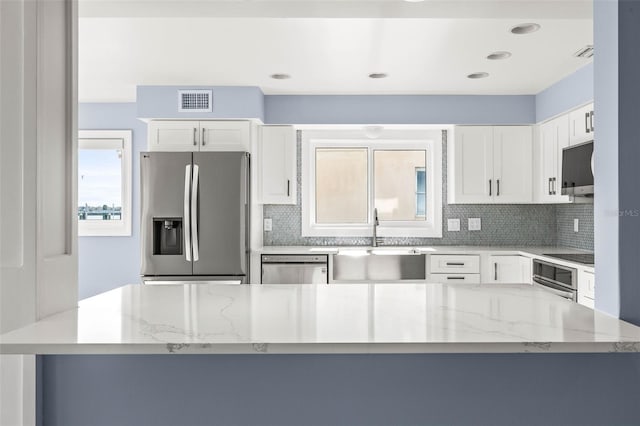 kitchen with a sink, light stone countertops, backsplash, and appliances with stainless steel finishes