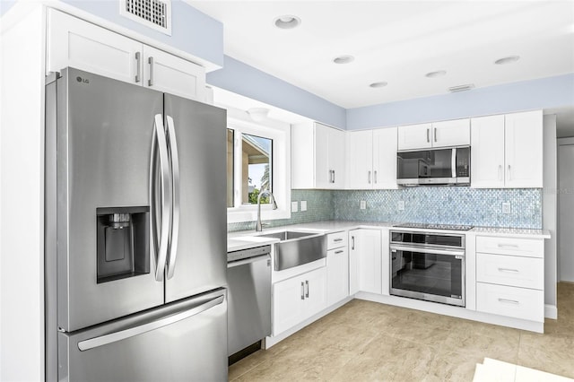 kitchen with light countertops, backsplash, appliances with stainless steel finishes, and a sink