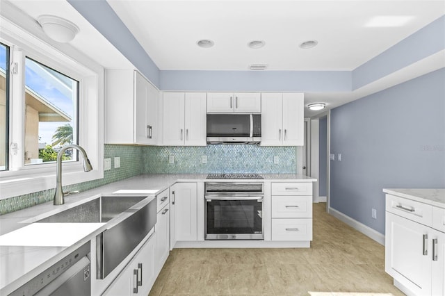 kitchen featuring visible vents, stainless steel appliances, white cabinets, decorative backsplash, and baseboards