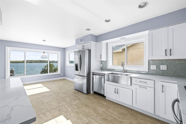 kitchen with tasteful backsplash, white cabinets, stainless steel appliances, and a sink