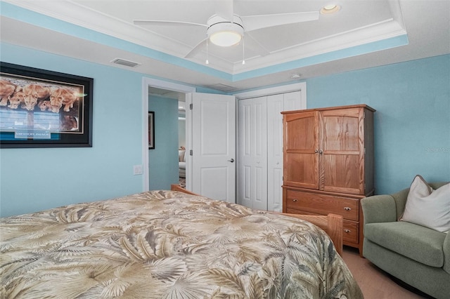 bedroom with visible vents, crown molding, ceiling fan, a tray ceiling, and a closet