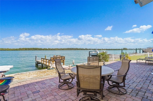 view of patio / terrace with outdoor dining space, fence, a water view, and a boat dock