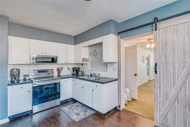 kitchen with dark wood-type flooring, a sink, dark countertops, a barn door, and stainless steel electric range oven