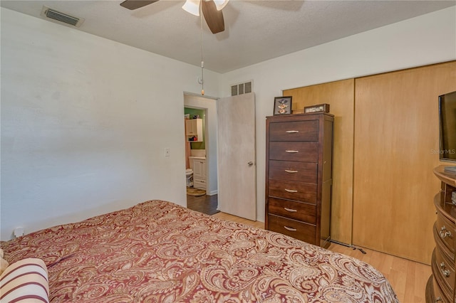 bedroom with a ceiling fan, visible vents, light wood finished floors, and a textured ceiling