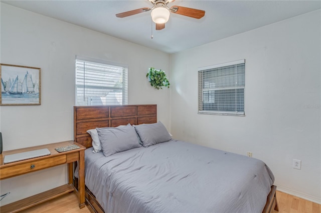 bedroom featuring baseboards, light wood-style floors, and a ceiling fan