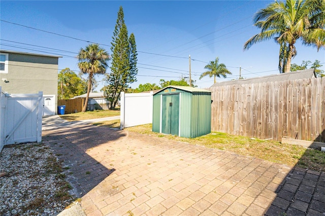 view of patio / terrace featuring a gate, a storage unit, an outdoor structure, and fence