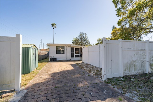 back of property with a storage unit, a patio, an outdoor structure, and fence