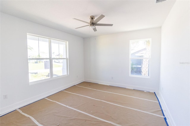 spare room featuring ceiling fan, visible vents, and baseboards