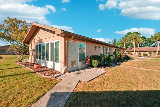 back of house featuring stucco siding and a lawn