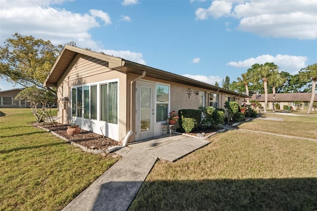 back of property featuring a lawn and stucco siding