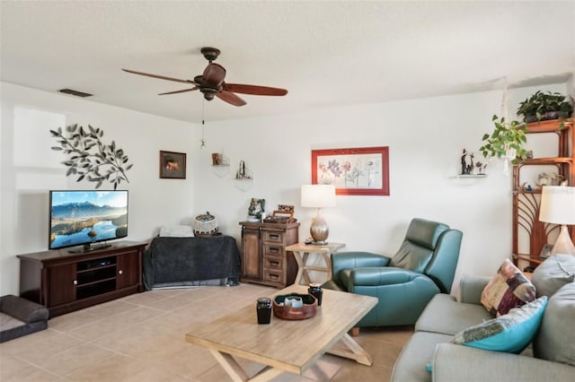 living room featuring light tile patterned floors, a ceiling fan, visible vents, and a textured ceiling