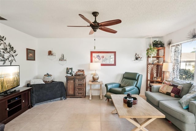 living room featuring a textured ceiling, light tile patterned floors, and ceiling fan