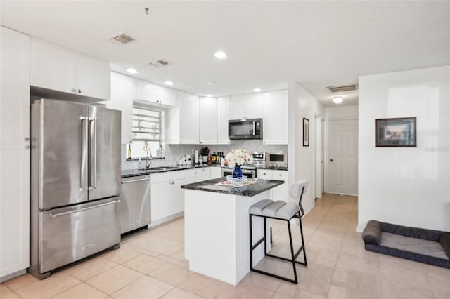 kitchen with tasteful backsplash, visible vents, appliances with stainless steel finishes, a kitchen breakfast bar, and white cabinets