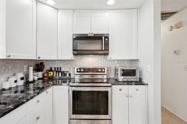 kitchen with white cabinetry, dark stone counters, electric stove, and tasteful backsplash