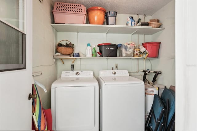 clothes washing area with independent washer and dryer and a textured ceiling