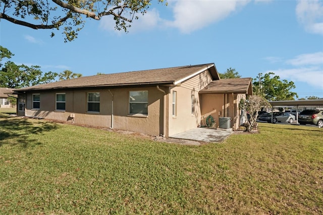 back of house featuring stucco siding, a yard, and central AC unit