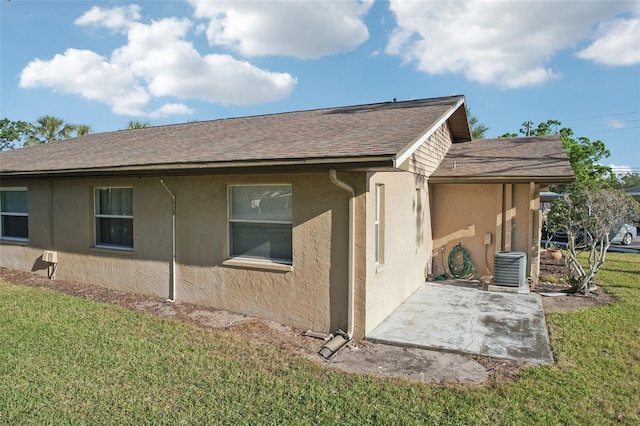 view of side of home featuring a yard, a patio area, roof with shingles, and stucco siding