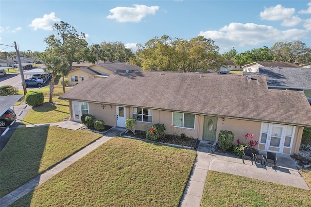 ranch-style house with stucco siding, a front yard, and roof with shingles