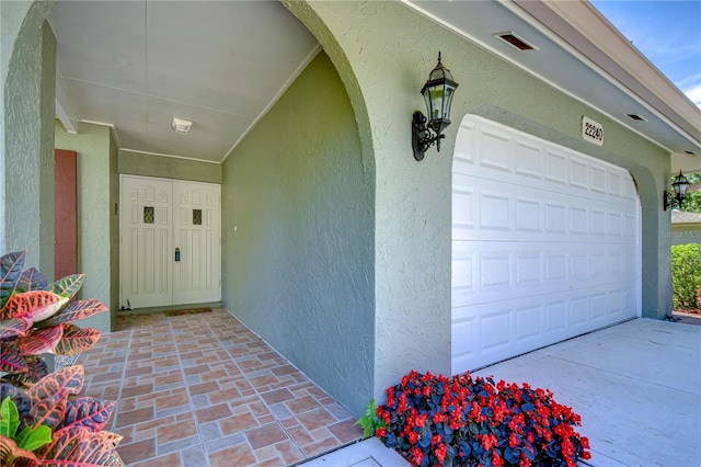 view of exterior entry with stucco siding and a garage