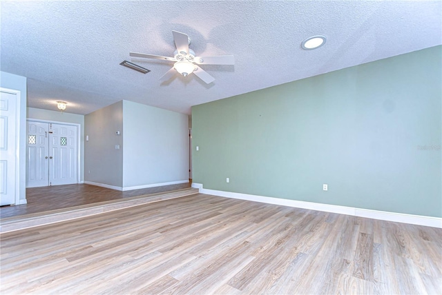 spare room with visible vents, a textured ceiling, light wood finished floors, baseboards, and ceiling fan