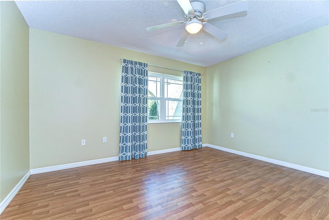 unfurnished room with baseboards, wood finished floors, and a ceiling fan