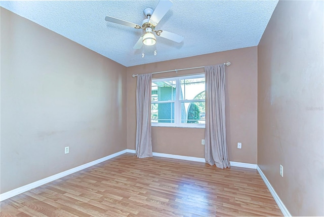 spare room featuring baseboards, a textured ceiling, light wood-style flooring, and a ceiling fan