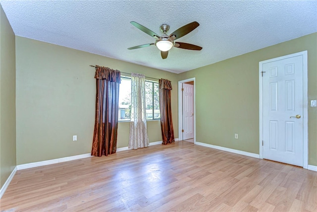 unfurnished room with a textured ceiling, light wood-style flooring, baseboards, and ceiling fan