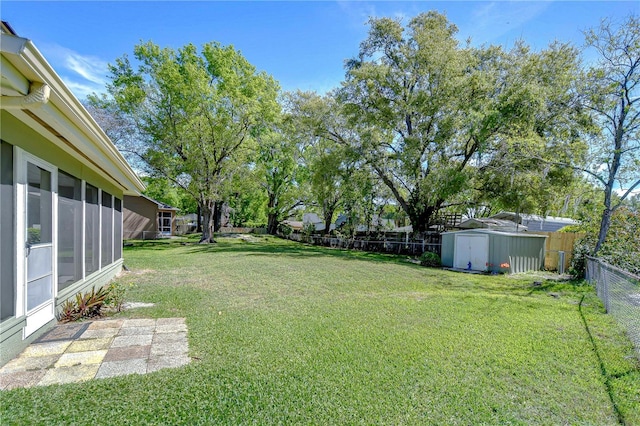 view of yard featuring an outdoor structure, a sunroom, a fenced backyard, and a shed