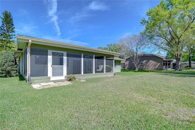 back of property with a lawn and a sunroom