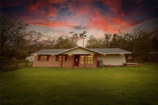 back of property at dusk with a yard and fence