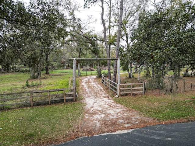 view of community featuring dirt driveway and fence