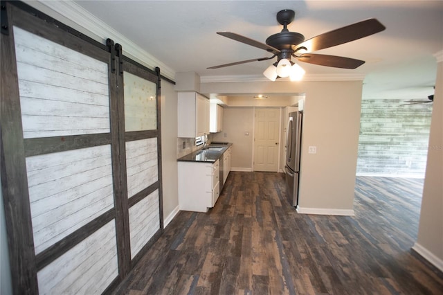 kitchen with a barn door, ceiling fan, crown molding, and freestanding refrigerator