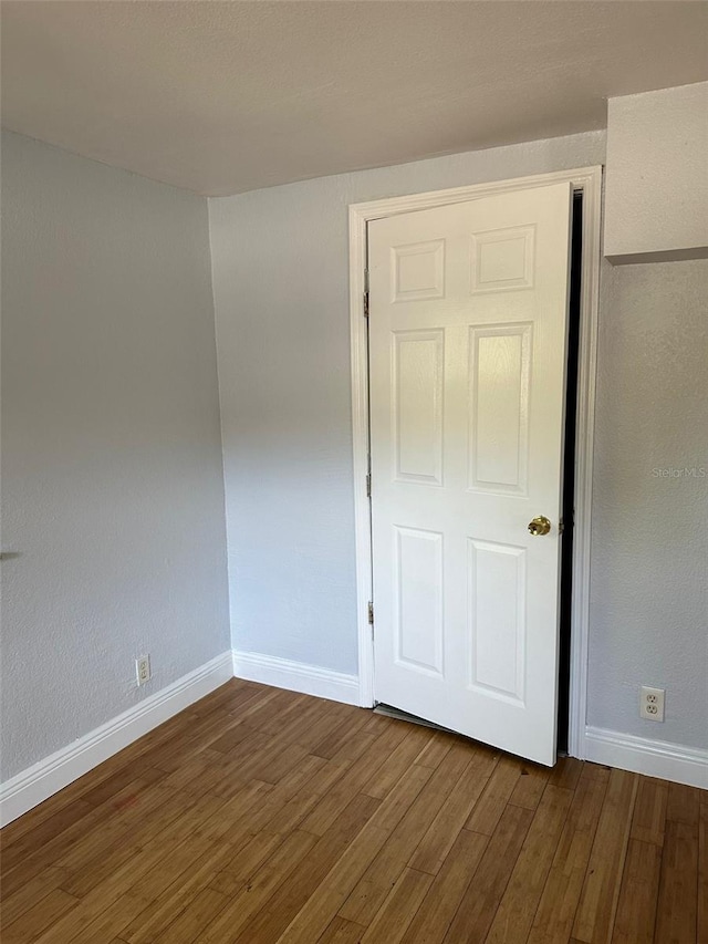 spare room with dark wood-style floors and baseboards