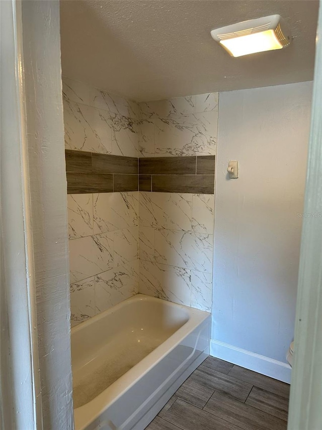 full bath featuring a textured ceiling, wood finished floors, toilet, and baseboards