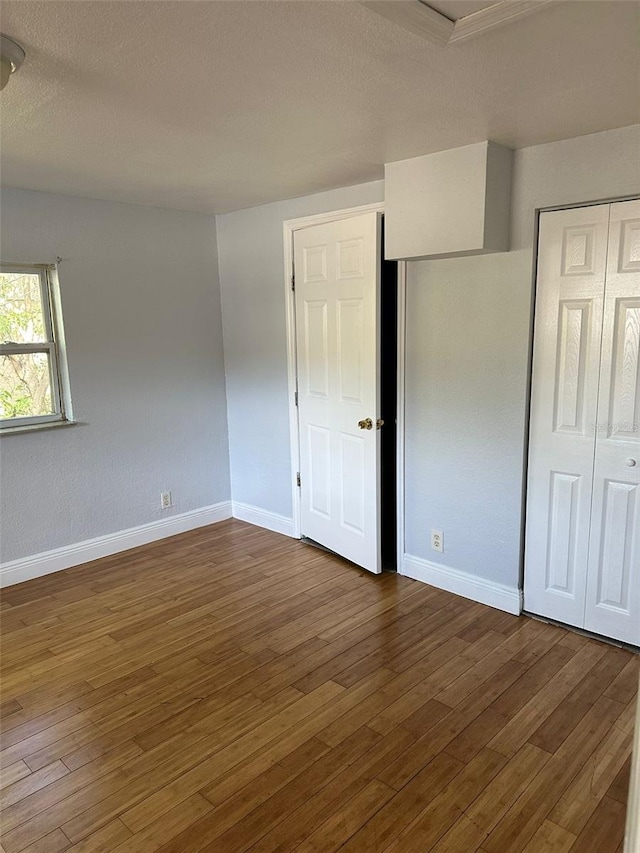 unfurnished bedroom featuring a closet, wood finished floors, and baseboards