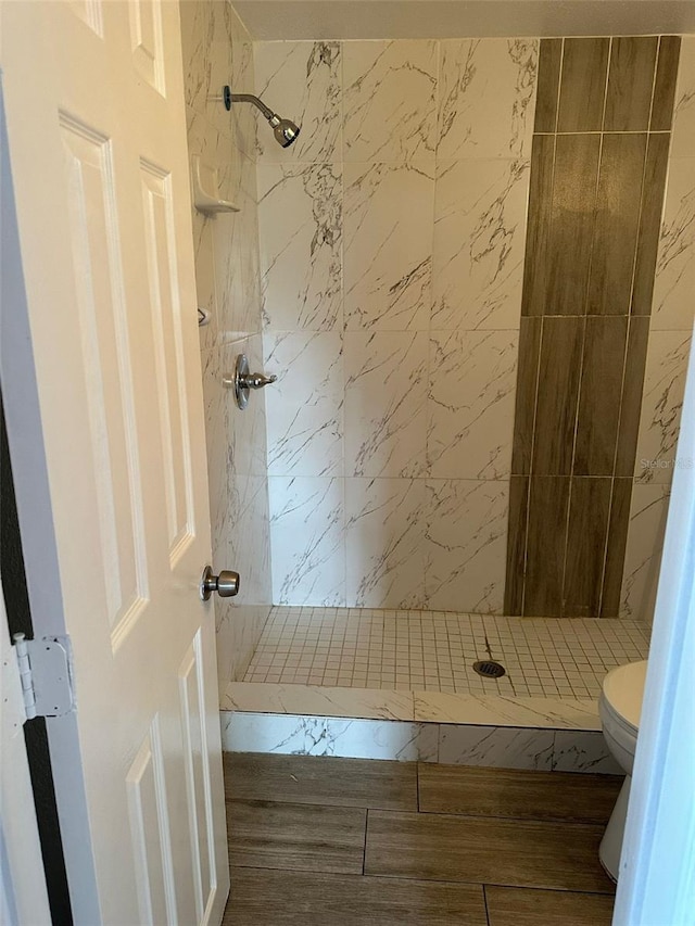 full bath with a tile shower and toilet