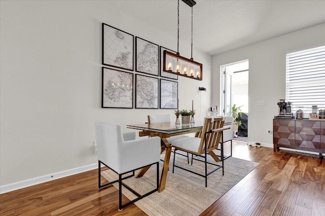 dining area with baseboards, an inviting chandelier, and wood finished floors