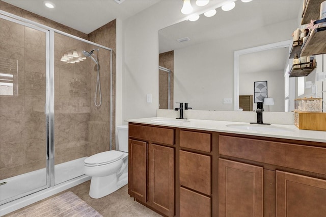 full bathroom featuring double vanity, a stall shower, toilet, and a sink