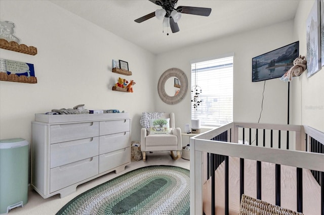 bedroom featuring carpet floors, a nursery area, and ceiling fan