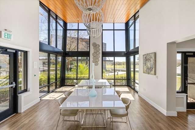 unfurnished dining area featuring a chandelier, floor to ceiling windows, wooden ceiling, and wood finished floors