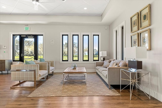 living room with wood finished floors, baseboards, and a paneled ceiling