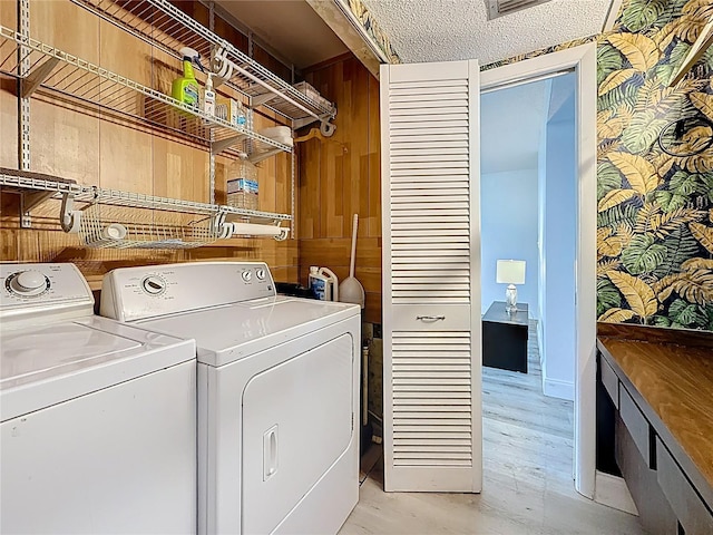 washroom with a textured ceiling, laundry area, and washing machine and clothes dryer