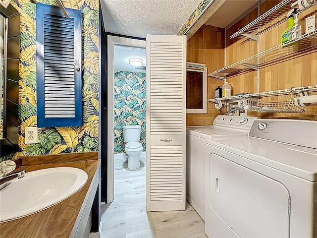 laundry room featuring a sink, a textured ceiling, light wood finished floors, laundry area, and washing machine and clothes dryer