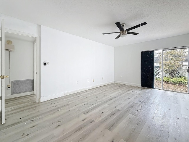 empty room featuring a ceiling fan, baseboards, wood finished floors, visible vents, and a textured ceiling