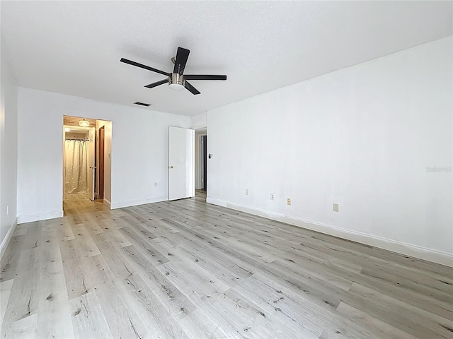 empty room with visible vents, baseboards, light wood-style floors, and a ceiling fan