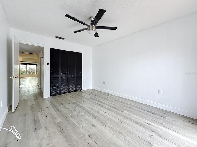 unfurnished bedroom featuring light wood-type flooring, visible vents, a ceiling fan, a closet, and baseboards