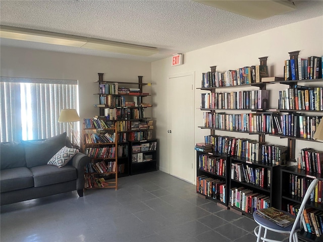 sitting room with a textured ceiling and wall of books